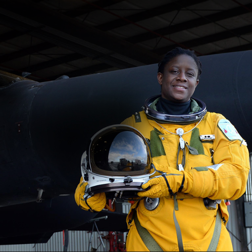 Military aircraft pilot in full high altitude suit holding a helmet