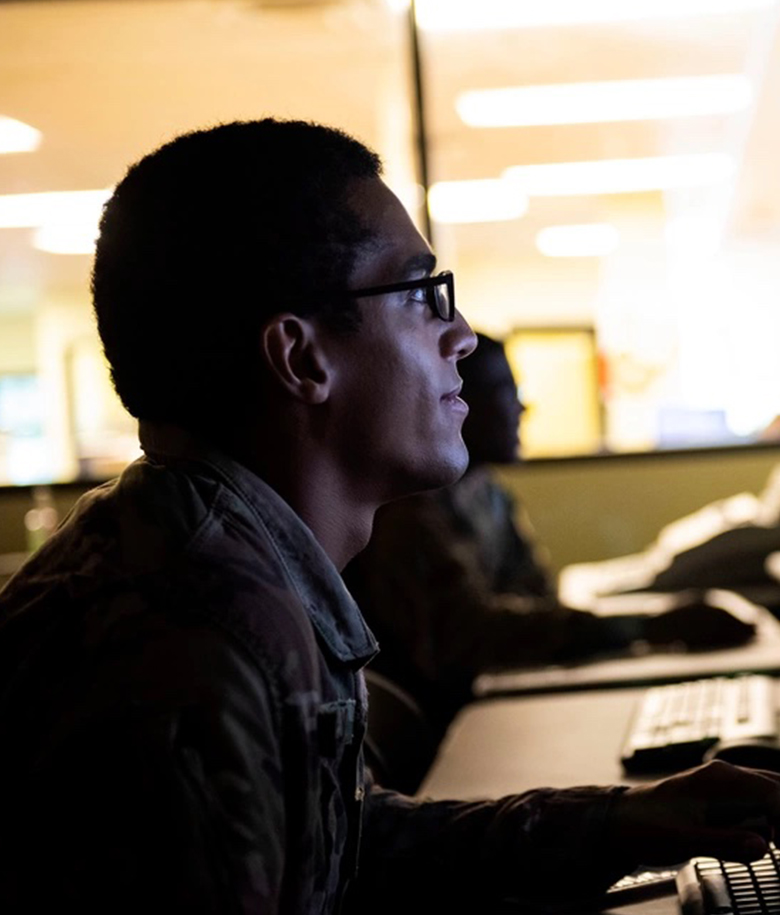 A Man Sitting At A Desk In Front Of A Computer