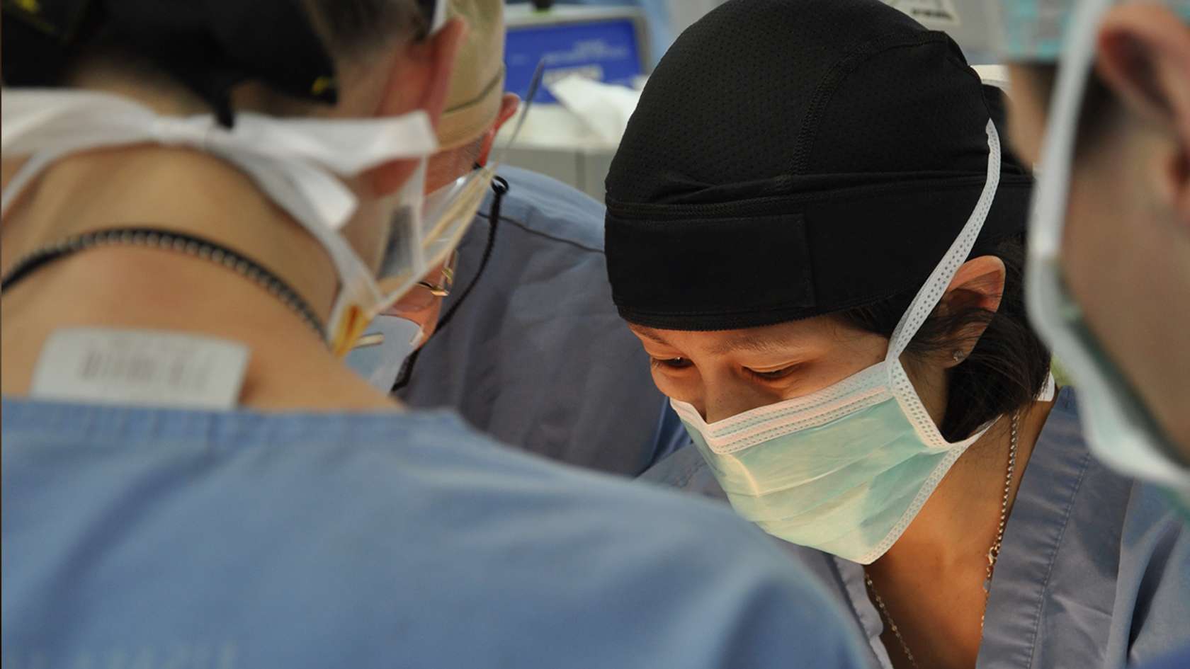 emergency trauma nurse wearing mask working on a patient with team