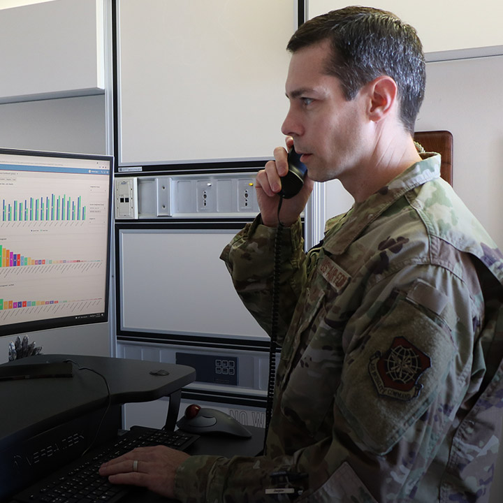 airman on the phone looking at a computer screen