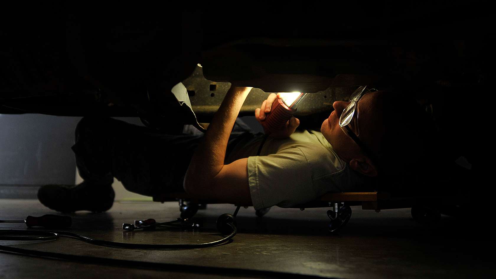 airman making repairs under a truck