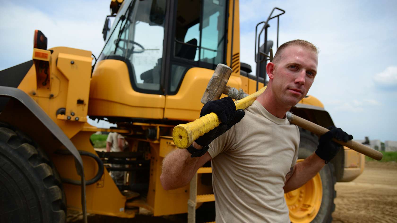 airman carrying tools in front of a forklift