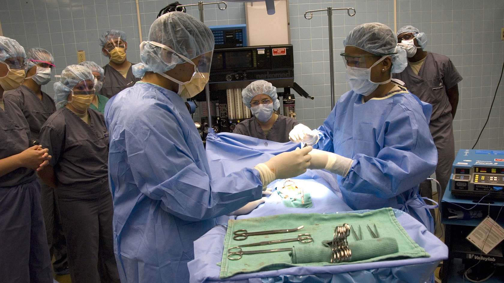 surgical team working on a patient with a group of people watching