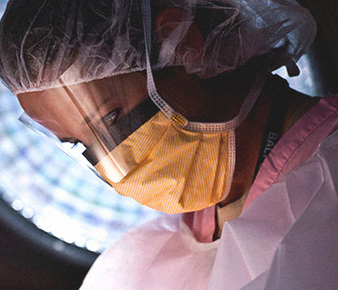 surgeon wearing a mask and hairnet examining