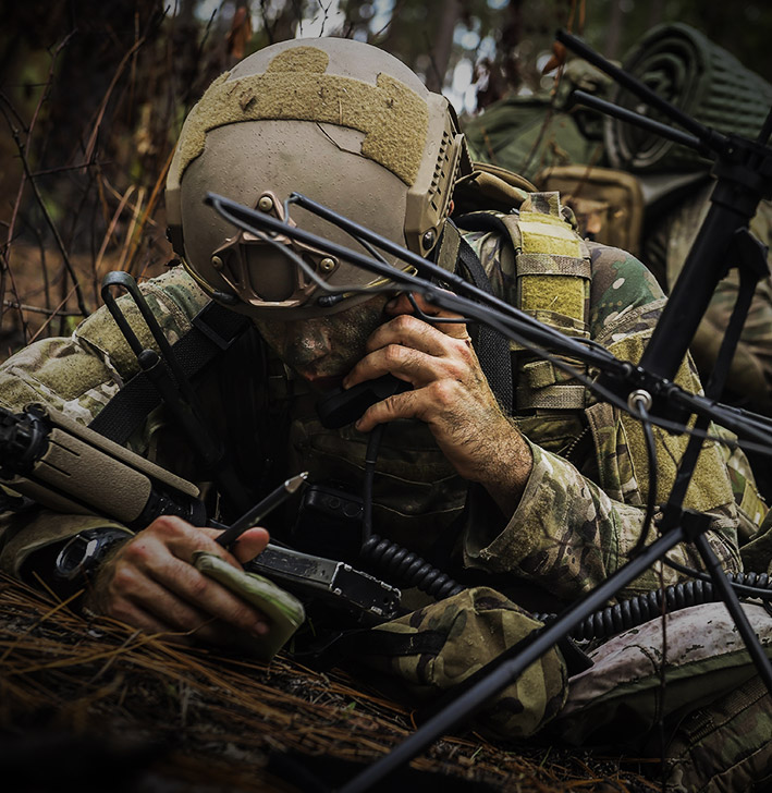 COMBAT CONTROLLER (CCT) communicating with someone via a phone with the rest of his team behind him ready for mission.