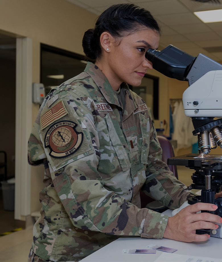 airman looking into microscope