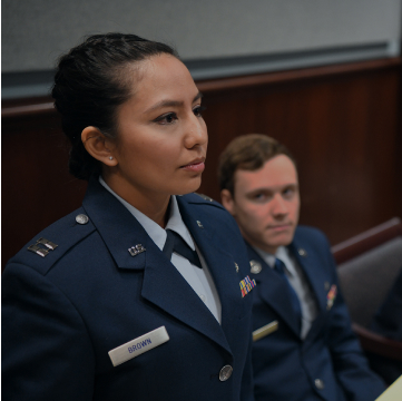 a female JAG attorney standing up, while another one sitting down is looking at her