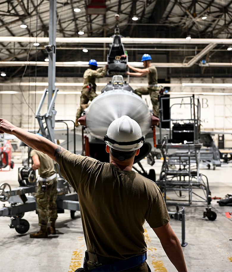 airman directing two other airmen to perform a precise coordination of aircraft seats