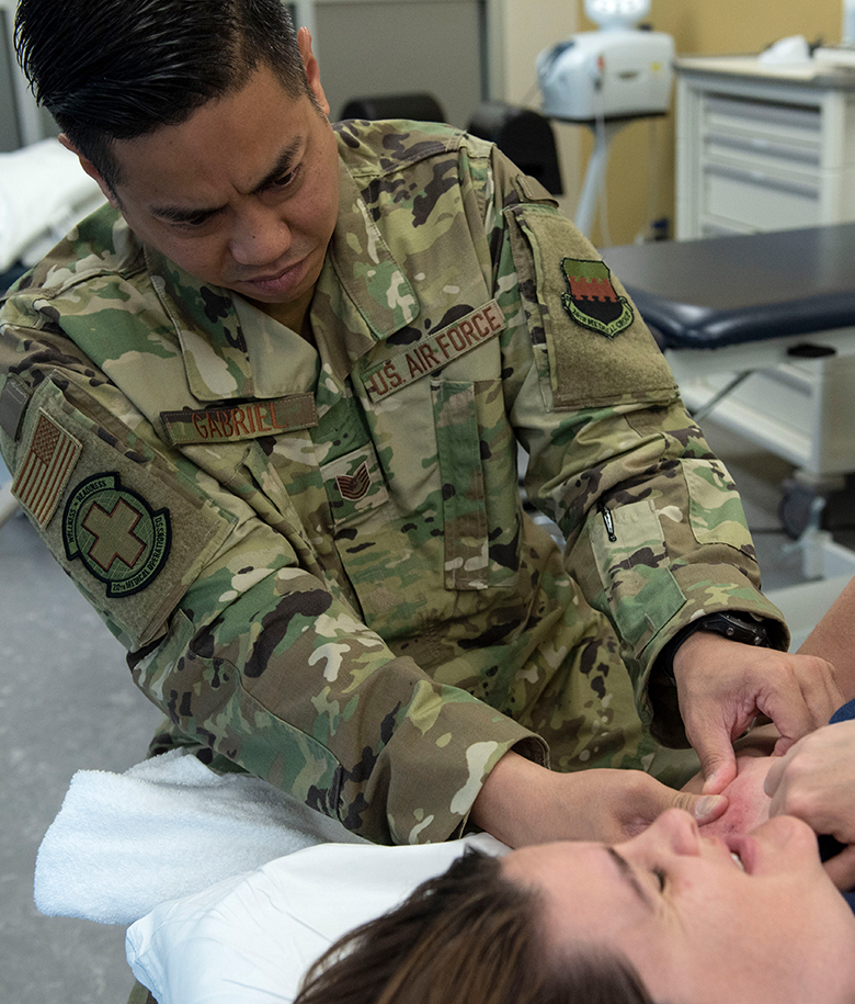 airman in uniform helping a patient with his shoulder