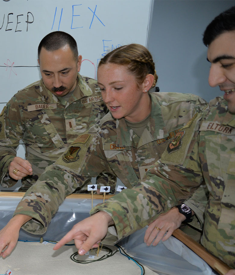 Information Operations Officers Gathered Around A Table Planning A Mission