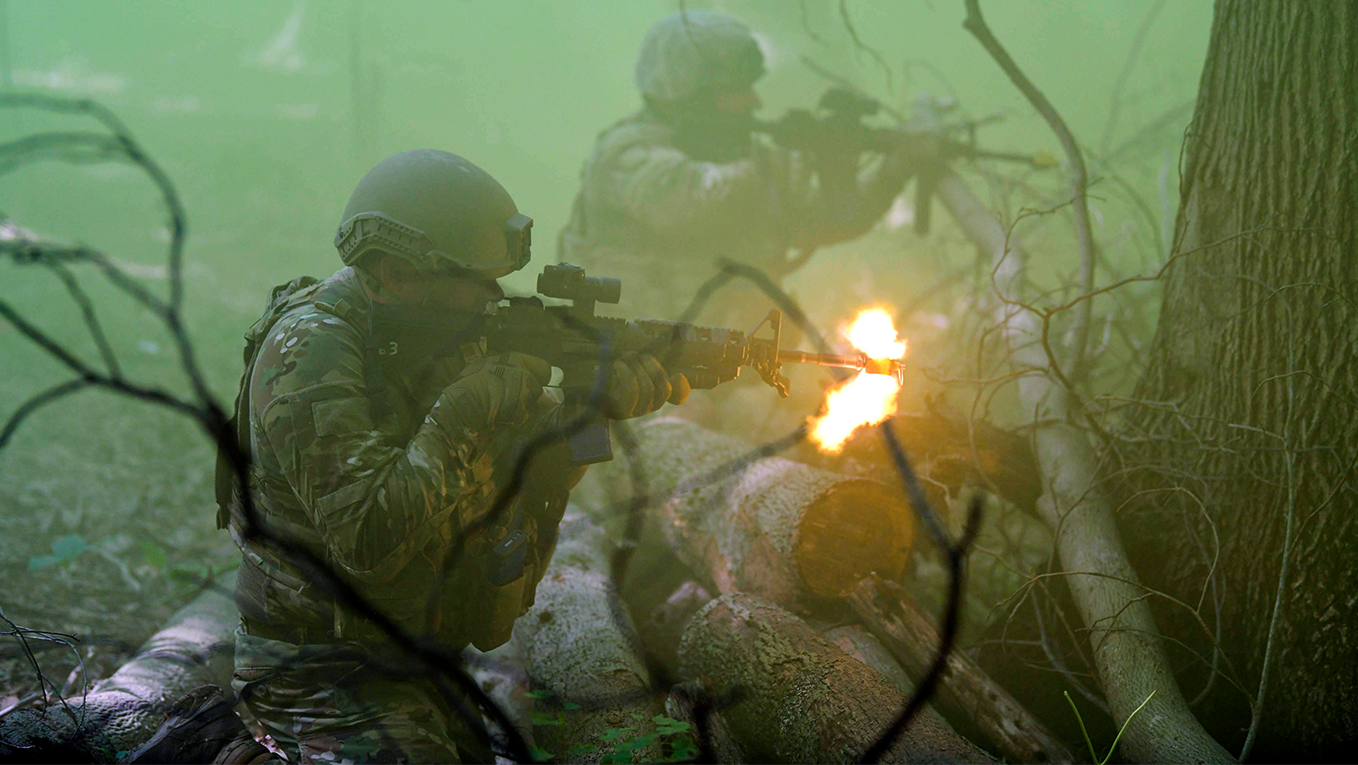 two airmen with firearms advancing towards a target