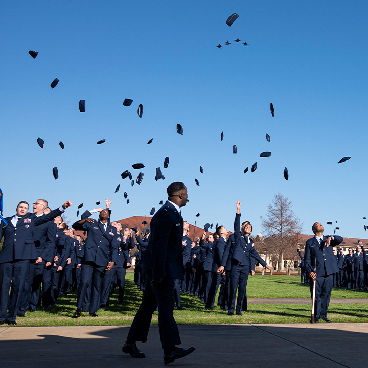 trainees throwing their cover in the air to celebrate their graduation