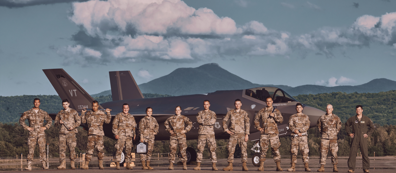 Airmen in front of an airplane in front of a volcano