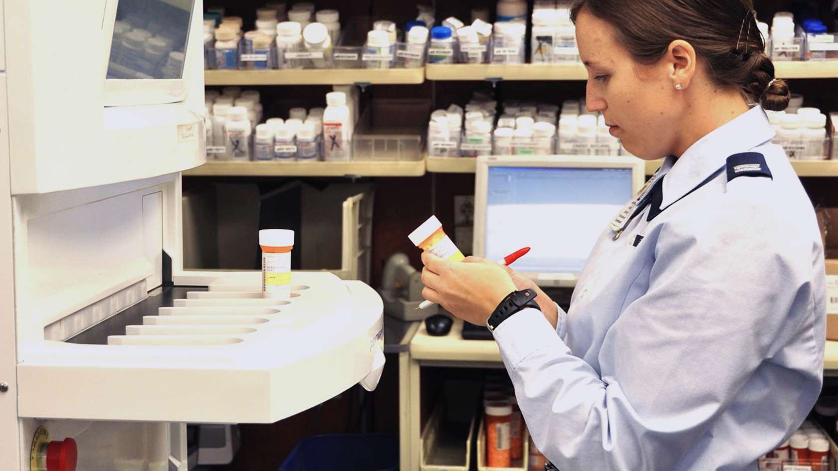 pharmacist inspecting patient's vial of meds