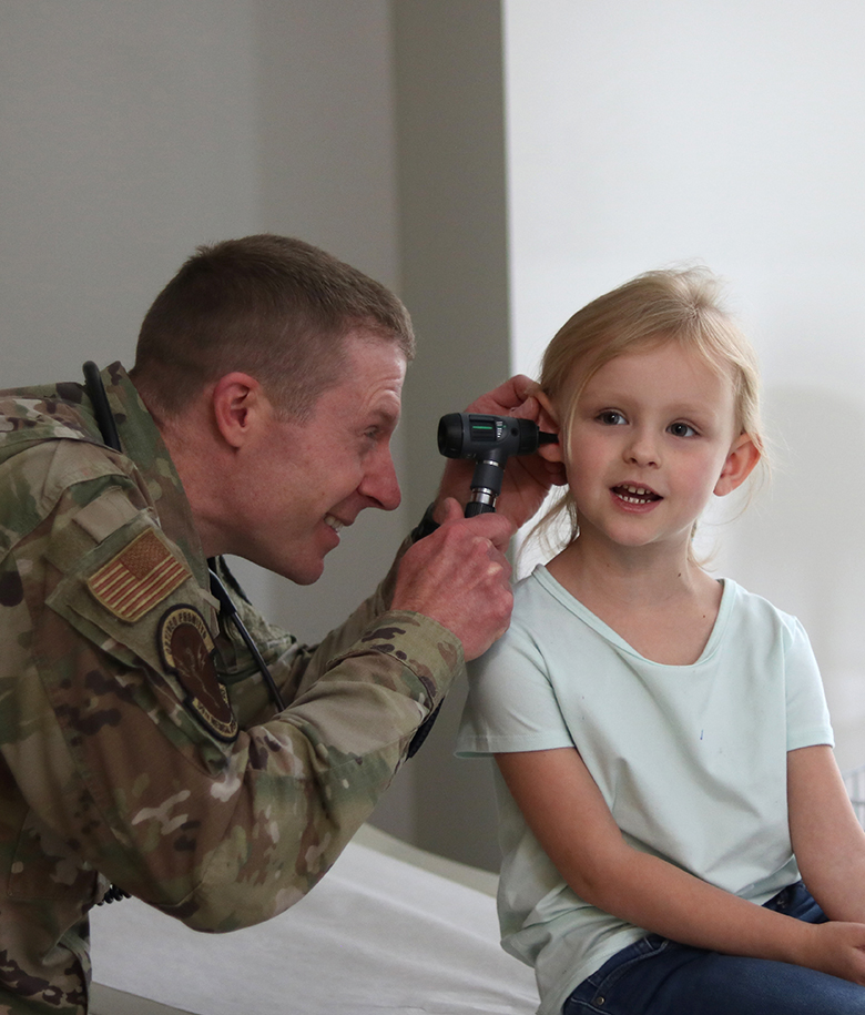 airman inspecting toddler's ear