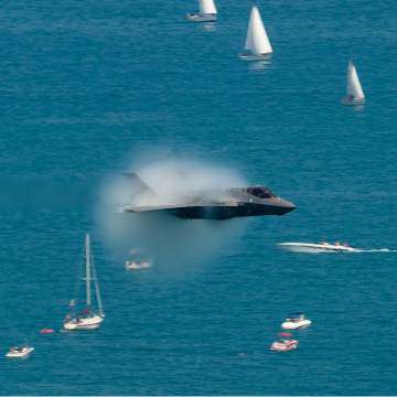 Fighter jet creating a sonic boom over water